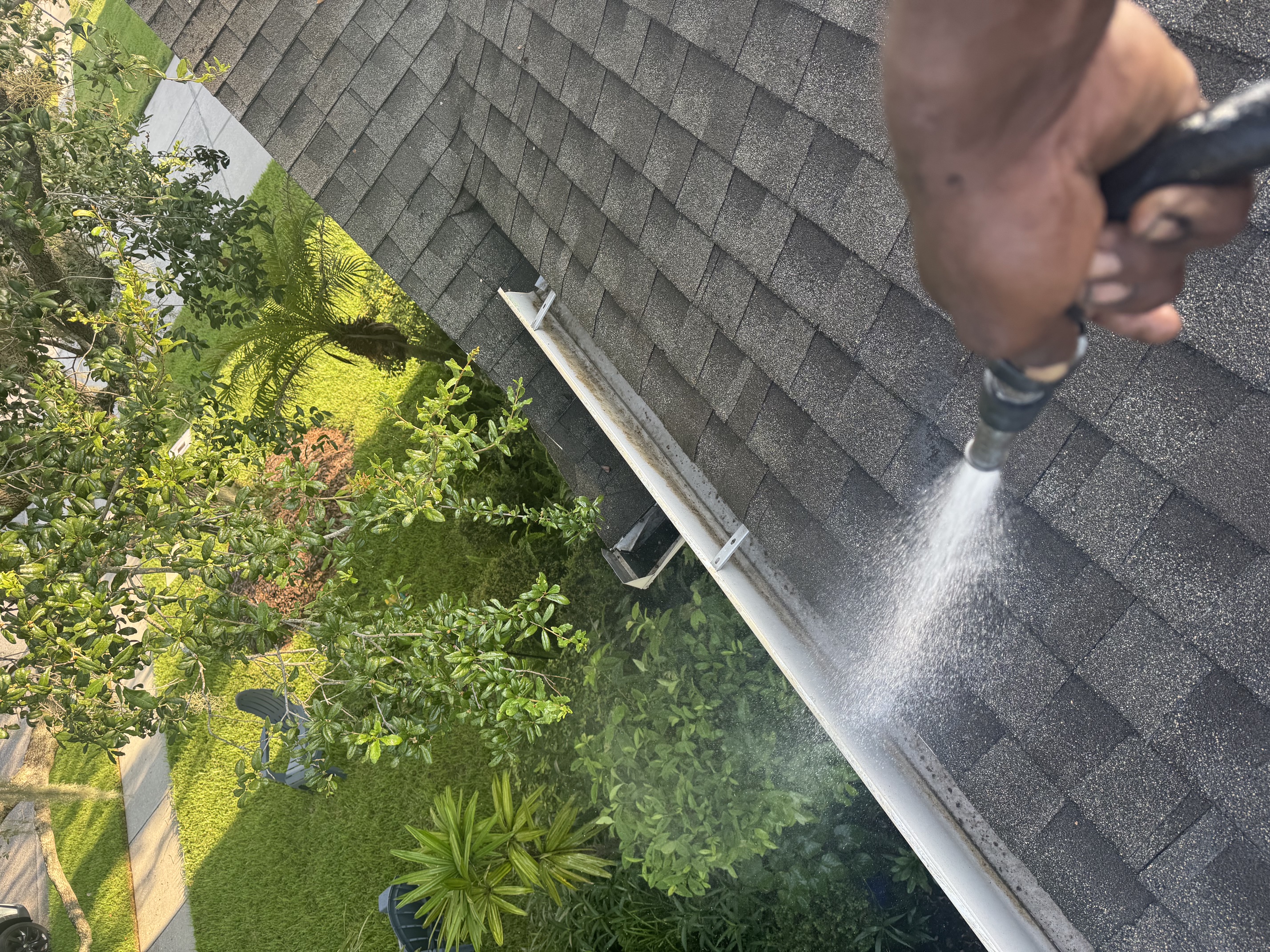 Pressure-rinsing the gutter line and roof edge after clearing debris