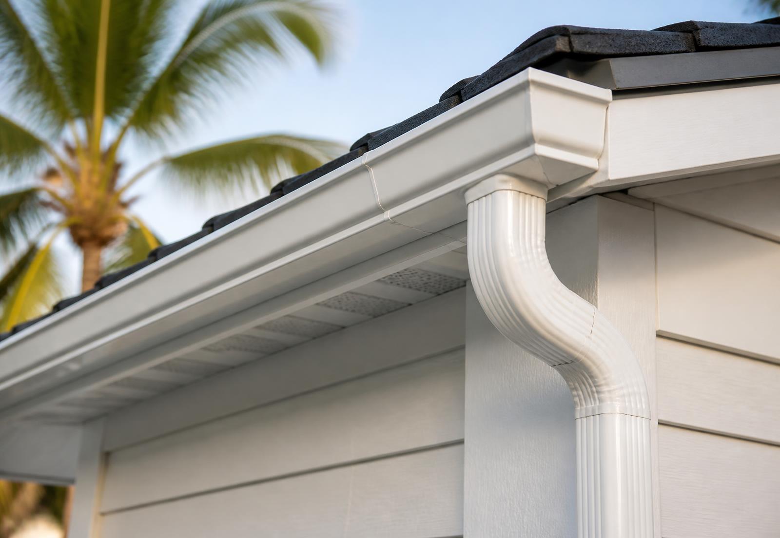Close-up of a white seamless aluminum gutter and downspout along the roof edge of a Florida home